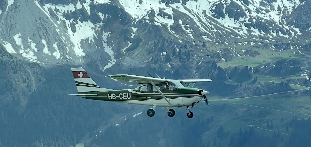 Fly4Fun’s Cessna 172 HB-CEU in flight in front of snow-covered mountain slopes
