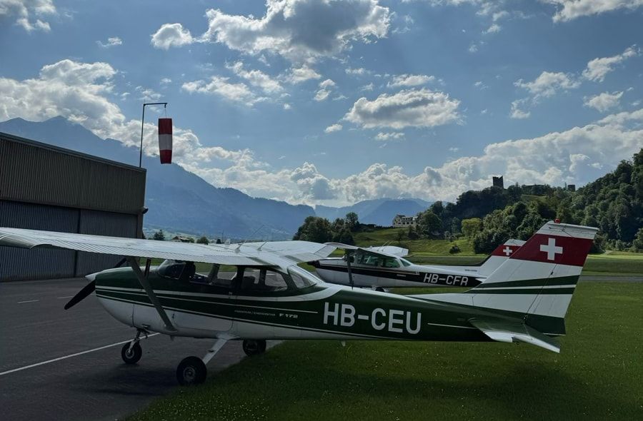 HB-CEU and HB-CFR side by side on the grass at Bad Ragaz airfield, a tower and mountains in the background