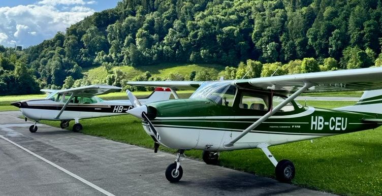 Die Cessna HB-CEU und eine zweite Cessna auf dem Vorfeld in Bad Ragaz vor bewaldeten Hängen